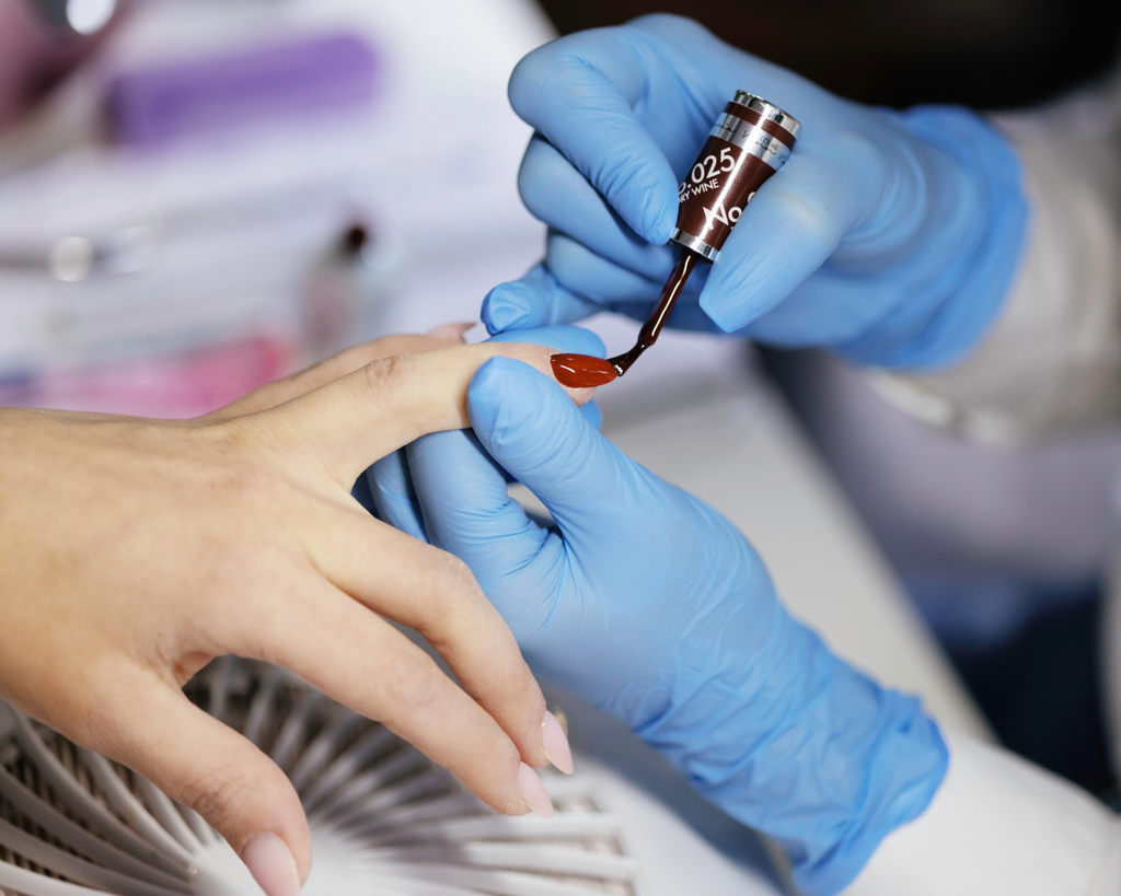 Eine Kundin kriegt Maniküre mit Lack im Kosmetikstudio